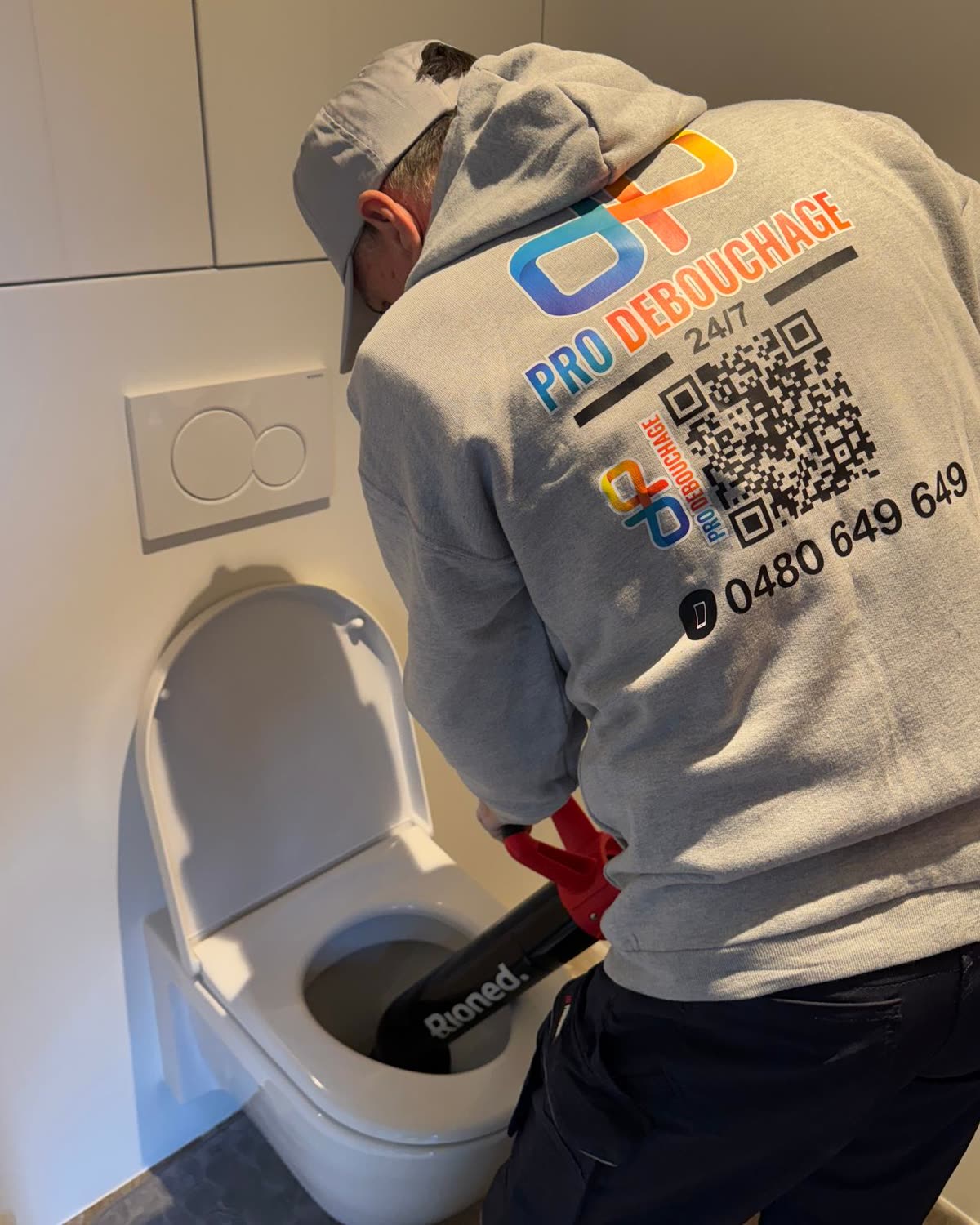Technicien qui débouche un WC avec un furet Rioned, veste Pro Débouchage.